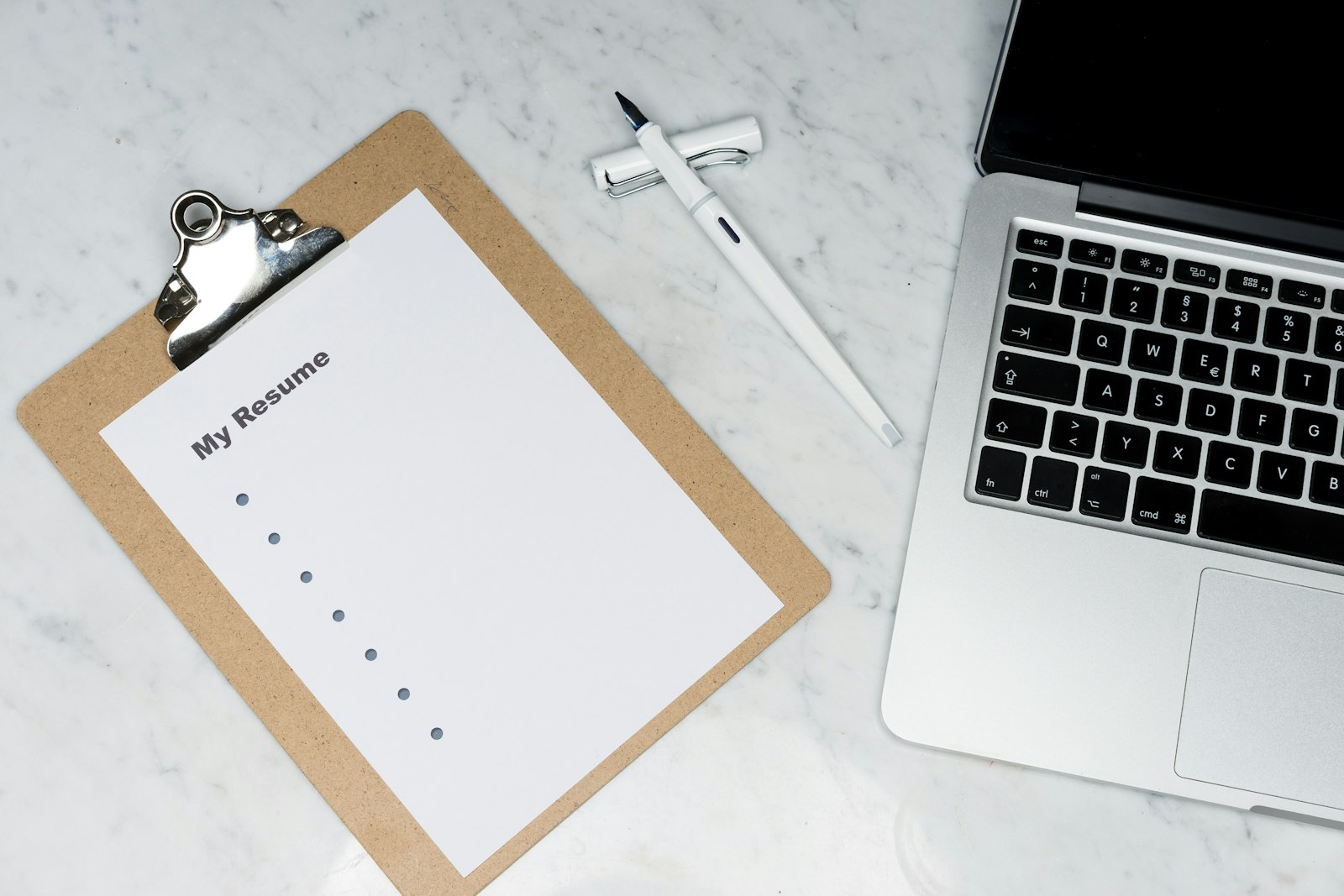 A printed resume titled 'My Resume' on a clipboard next to a laptop