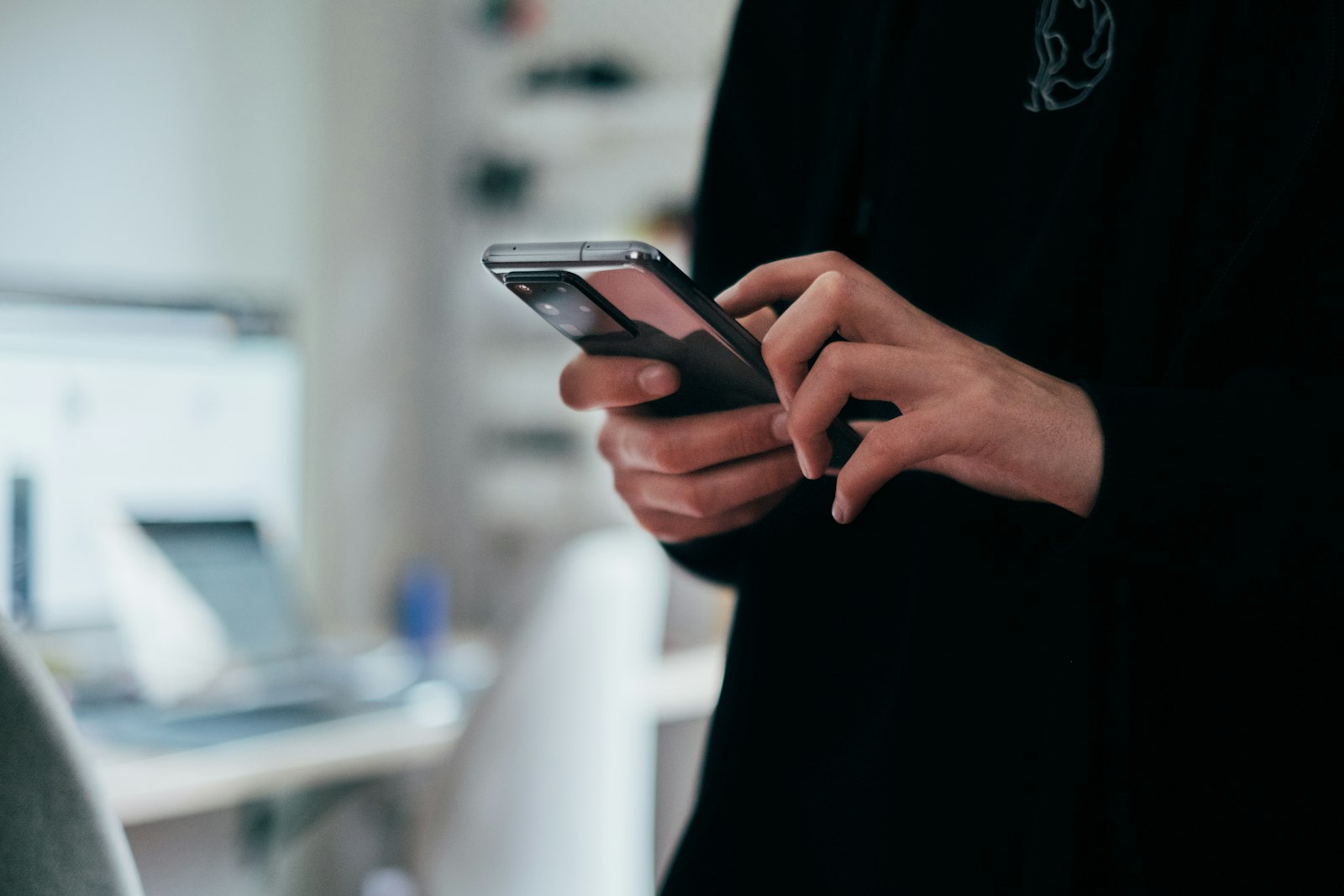 A person's hand holding a phone while typing a message