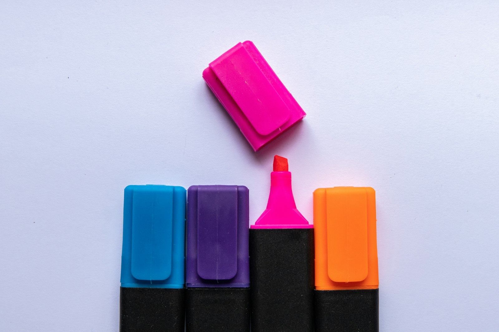Four colorful highlighter markers lined up on a light purple background