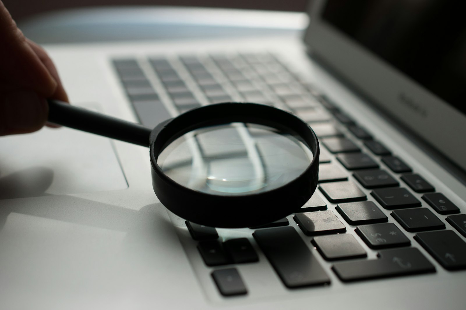 A magnifying glass resting on a laptop keyboard